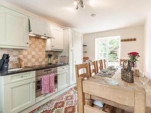 StocksfieldKeepers Cottage的厨房配有白色橱柜和桌椅