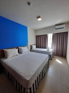 塞古罗港Resort Ondas Praia apart的蓝色墙壁的酒店客房内的两张床