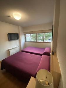 马德里马德里埃斯库埃拉酒店的一间卧室设有紫色的床和窗户