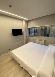 马德里马德里埃斯库埃拉酒店的卧室配有一张白色大床和一台平面电视。