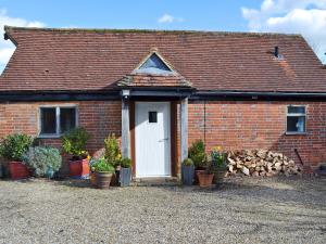 West HoathleyHoney Meadow Cottage的砖房,有白色门和盆栽植物