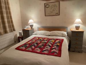 米尔登霍尔Silver Lodge Guest House的一间卧室配有一张床铺,床上铺有红色毯子