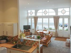 拉姆斯盖特海景度假屋的厨房以及带桌椅的起居室。
