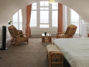 拉姆斯盖特海景度假屋的一间卧室配有一张床、椅子和窗户。