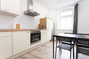 开姆尼茨Schickes 1-Raum-Apartment mit Balkon und vollausgestatteter Küche的厨房配有白色橱柜和桌椅