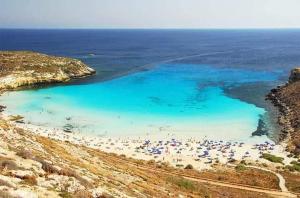 兰佩杜萨Élite Lampedusa的海滩上有遮阳伞和水中的人