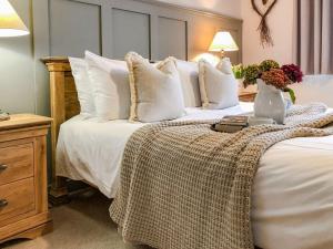 LlanwrdaMaes Y Bryn Farmhouse的一张带白色枕头的床和花瓶