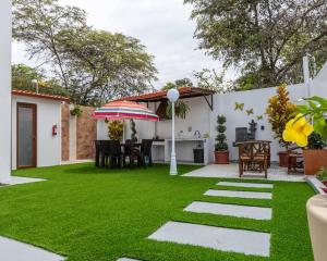 马查利亚Hermosa Casa de Playa Machalilla的后院有草地、雨伞和桌子