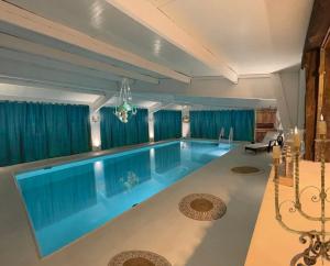 Marais-Vernier7eme ciel - Tiny House avec Grande Piscine intérieure chauffée toute l'année的一座带蓝色窗帘的别墅内的大型游泳池