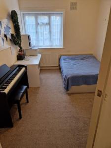 伦敦Double room for One Person in 3 beds flat的卧室配有床、书桌和钢琴