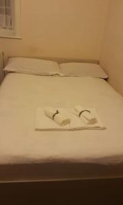 伦敦Double room for One Person in 3 beds flat的一张白色的床,上面有两条毛巾