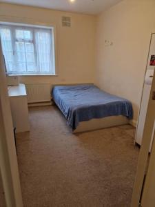 伦敦Double room for One Person in 3 beds flat的一间卧室配有一张带蓝色床罩的床和窗户。
