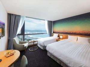 蔚山Mercure Ambassador Ulsan的酒店客房设有两张床和大窗户。