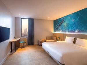曼谷ibis Styles Bangkok Ratchada的酒店客房设有一张大床和一张书桌。