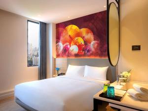 曼谷ibis Styles Bangkok Ratchada的一间酒店客房,配有白色的床和绘画作品