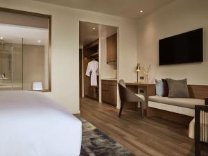 富国Mövenpick Villas & Residences Phu Quoc的酒店客房设有一张床、一张书桌和一台电视机。