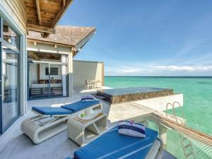 马纳杜岛Mӧvenpick Resort Kuredhivaru Maldives的一座带椅子和大海的甲板的房子