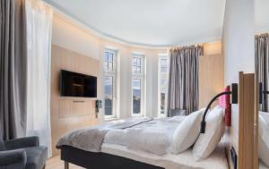 卑尔根Bergen Harbour Hotel, WorldHotels Crafted的一间卧室设有一张床、一台电视和窗户。