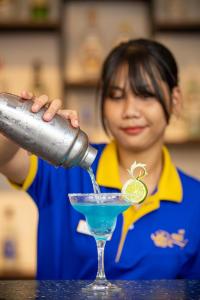 金边Nangkol Village的把蓝色饮料倒进马提尼玻璃中的女人