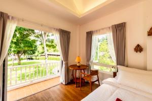 清迈Phi Private Villa: Luxury Thai with Riverview的一间卧室设有一张床、一个窗口和一张桌子