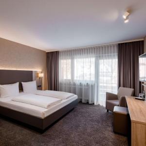 Donzdorf贝彻酒店的酒店客房带一张床、椅子和窗户
