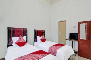 北干巴鲁OYO 92135 A3 Homestay Syariah Executive的配有红色和白色床单的客房内的两张床