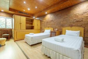 曼谷PJ水门酒店的一间卧室设有两张床和石墙