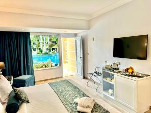 亚历山大天堂海滩度假酒店的一间卧室设有一张大床和一台平面电视。
