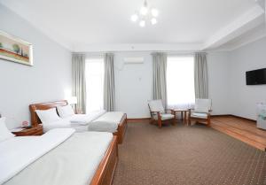 苦盏Khujand Grand Hotel的酒店客房带两张床和一张桌子以及椅子。