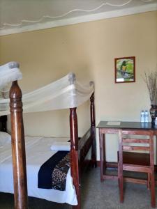 MasindiPross Residence的一间卧室配有一张天蓬床和一张书桌