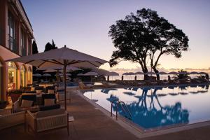 丰沙尔Reid's Palace, A Belmond Hotel, Madeira的游泳池旁设有椅子和遮阳伞