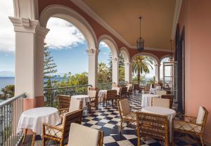 丰沙尔Reid's Palace, A Belmond Hotel, Madeira的阳台餐厅,配有桌椅
