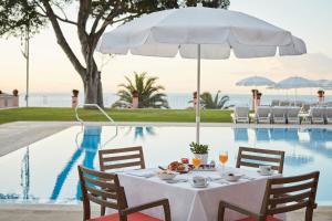 丰沙尔Reid's Palace, A Belmond Hotel, Madeira的一张餐桌,旁边配有白色遮阳伞