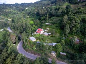图利凯尔Hasera Organic Farmstay: Farm to Table & Mountain View的享有山丘上房屋空中景观和道路