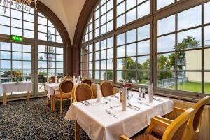 克林克Seehotel Schloss Klink的餐厅设有桌椅和大窗户。