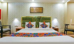 新德里FabHotel Aerosky Grand的一间卧室配有一张大床和一把椅子