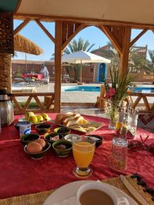 扎古拉Oasis Tilogui的一张桌子,上面有食物和饮料,放在红色桌布上