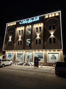 Al Mikhlafالشرق بارك للشقق المخدومة的一座大建筑,晚上有标志