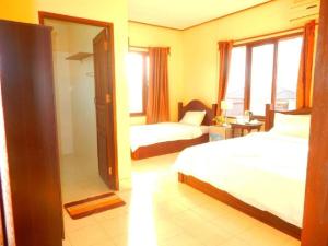 万荣Vang Vieng Camellia Hotel的酒店客房设有两张床和窗户。