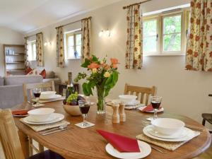 比灵斯赫斯特Woodlands Dairy Cottage的用餐室配有带葡萄酒的木桌