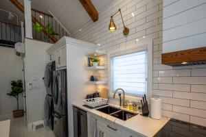 基奇纳Kingsdale Designer Tiny House with Tesla Charger的白色的厨房配有水槽和冰箱