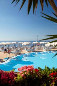 丰沙尔波尔图湾度假酒店的海滩上带椅子和遮阳伞的游泳池
