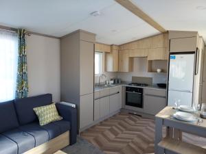 新米尔顿Hoburne Bashley Self-Catering Holiday Home的一间带蓝色沙发的客厅和一间厨房