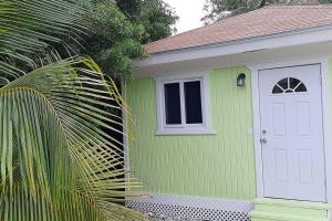 拿骚Budget & Basic in Local Neighborhood, 7min Drive to Downtown Nassau Beach Paradise的绿色的房子,有白色的门和窗户