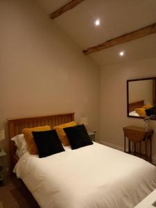 斯基普顿Henry's Cottage的卧室配有白色床和2个黑色枕头