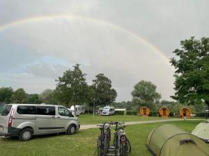 多瑙河畔埃默斯多夫Donaucamping Emmersdorf的一辆停放在田野的面包车,里面设有自行车和帐篷