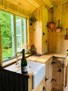 查尔伍德The Big Green Shepherds Hut的厨房配有水槽和一瓶葡萄酒