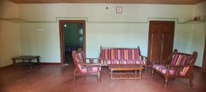 贾夫纳Aache Veedu Farm House的一间设有三把椅子、一张桌子和一张桌子及椅子的房间
