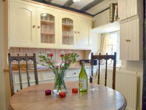 阿什比圣勒杰斯Rebeccas Cottage的一张桌子,上面放着一瓶葡萄酒和鲜花