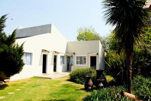 伊登维尔La Coscello Guest House的院子里有棕榈树的白色房子